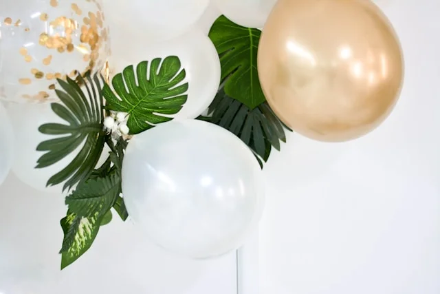 White and gold celebration balloons that are attached to the wall.