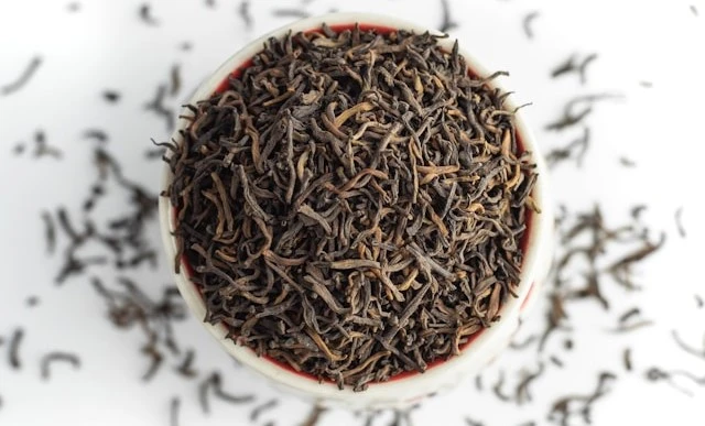 A pottery bowl filled to the brim of dried-up black tea leaves