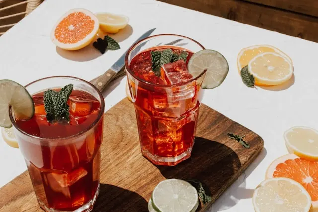 Two bourbon sweet tea drinks in glass cups with mint leaves and orange slices as a garnish