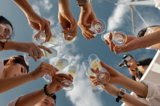 Multiple people cheers with cocktail glasses during an outside summer party.