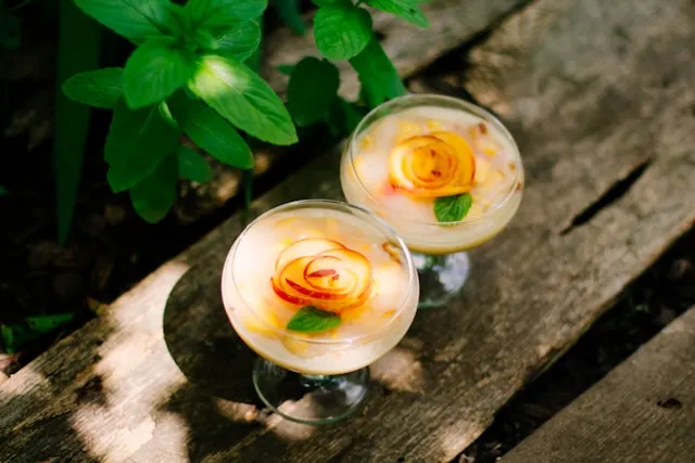 Peach green tea vodka spritzer with many thin slices of peaches as a garnish on top of the glass cup.