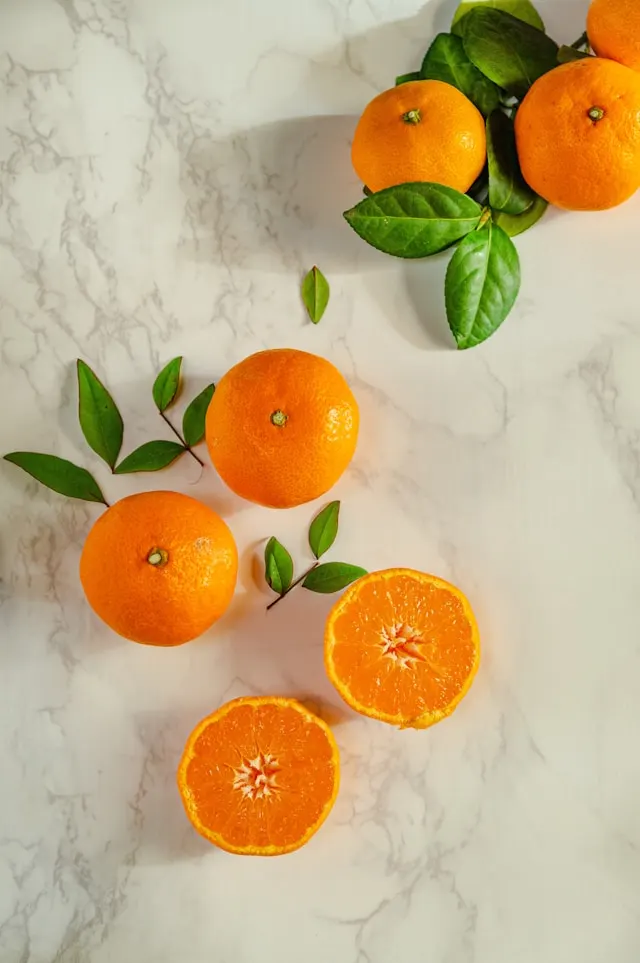 Cut-up oranges and whole oranges displayed on a white counter