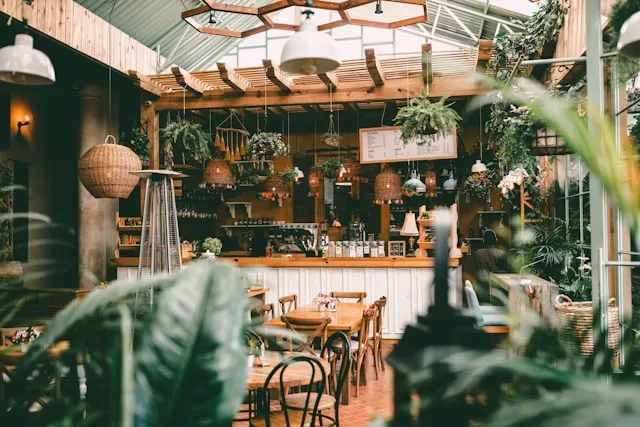 Beige and greenery room that shows the tea and alcohol bar and wooden tables.