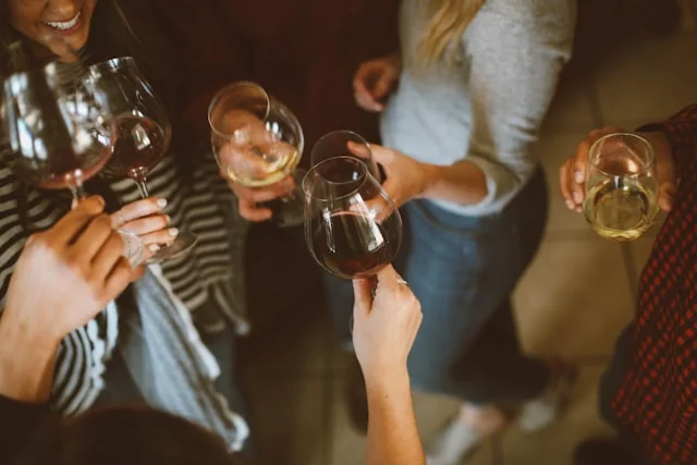 Group of women hanging out while laughing and cheers each other with their drinks.  